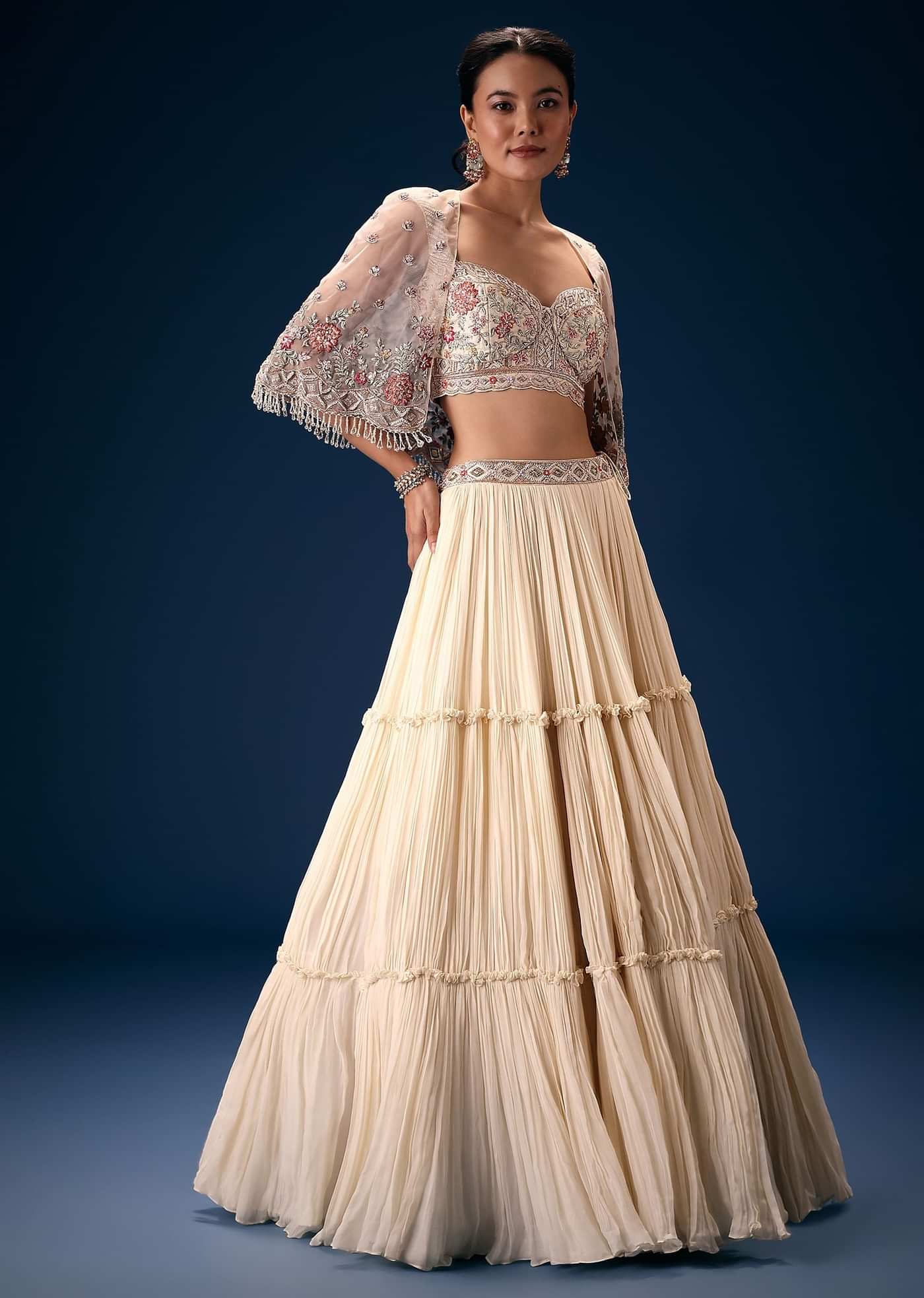 Off White Tiered Lehenga With Embroidered Corset Blouse And Embroidered Cape